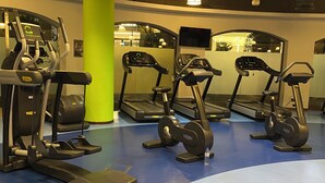 Een sportschool met loopbanden, elliptische trainers en een waterfles op de vloer.