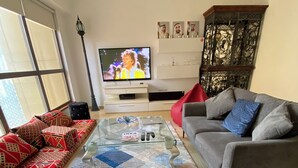 Een woonkamer met een bank, een glazen salontafel en een televisie op een meubel.