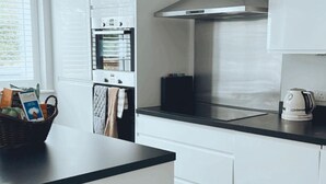 A modern kitchen with white cabinets, a black countertop, and a stainless steel range hood.