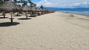 A beach with thatched umbrellas and lounge chairs. - Playa Royale Tower One Studio (Nuevo Vallarta)