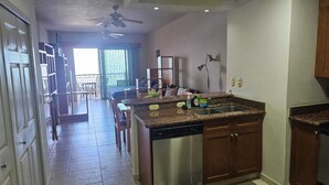 A kitchen with a dishwasher, granite countertops, and wooden cabinets. - Playa Royale Tower One Studio (Nuevo Vallarta)