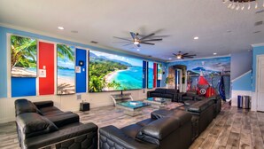 A modern living room with a large sectional sofa, a glass coffee table, and a ceiling fan.