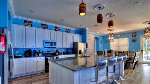 A modern kitchen with white cabinets, a granite countertop, and a central island with bar stools.