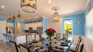 A modern kitchen with white cabinets, stainless steel appliances, and a dining area with a glass table set for six.