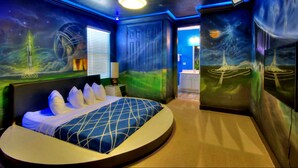 A bedroom with a curved bed, a night sky mural, and a door leading to a bathroom.