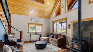 Un salon chaleureux avec une cheminée, un plafond en bois et des sièges confortables.
