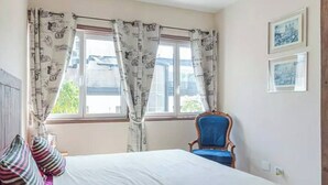 Un dormitorio con una cama, una silla y dos cuadros en la pared.