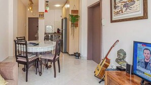Un comedor con una mesa redonda y sillas, un televisor y una guitarra.