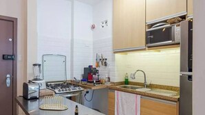 Una cocina compacta con estufa a gas, microondas y un lavamanos pequeño.
