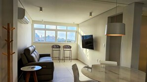 Ett modernt vardagsrum med en soffa, två fåtöljer, ett matbord och en tv som är monterad på väggen.