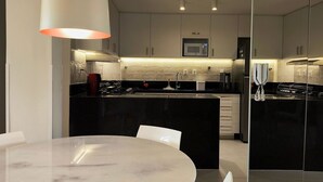 A modern kitchen with a central island, white cabinets, and a microwave above the sink.