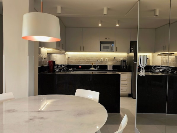 A modern kitchen with a central island, white cabinets, and a microwave above the sink.