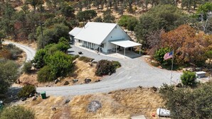 A white building with a sloped roof, surrounded by trees and a gravel driveway. - Beulah Land Only 4 Miles from SNP! (Three Rivers)