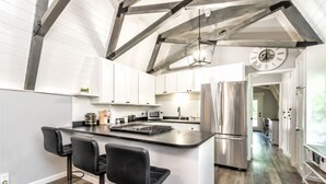 A modern kitchen with a central island, stainless steel appliances, and a large clock on the wall.
