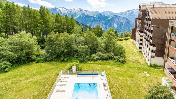 A swimming pool surrounded by lush greenery and mountains in the background.