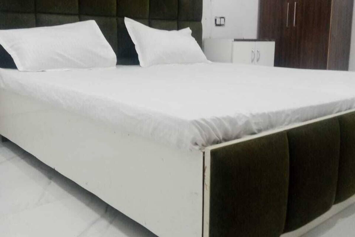 Ein Bett mit dunklem Kopfteil und weißer Bettwäsche in einem Zimmer mit Marmorboden.