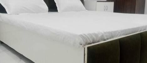 A bed with a dark headboard and white bedding in a room with a marble floor.