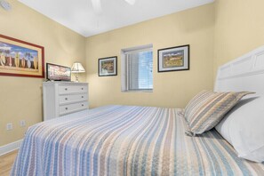 Une chambre à coucher avec un lit, une commode, une fenêtre et des œuvres d’art murales.