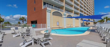 Un hôtel doté d’une piscine, de chaises longues et d’un bâtiment avec des balcons.