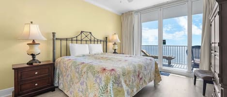 A bedroom with a bed, two bedside lamps, a ceiling fan, a balcony with a view, and a nightstand.