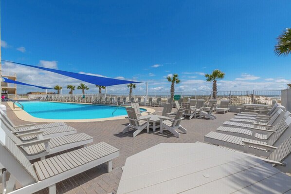 A pool area with lounge chairs and umbrellas.