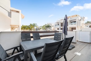 Een terras op het dak met een tafel en stoelen, een pergola en uitzicht op moderne gebouwen.