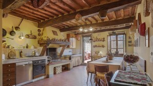 A rustic kitchen with wooden beams, a dining area with a table and chairs, and a view of the outside. - Room 'Ginepro Double  - First Floor' with Shared Terrace and Wi-Fi (Montecarlo)