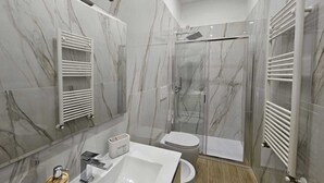 Ein modernes Badezimmer mit großem Spiegel, Waschbecken in Weiß, Toilette und einer Duschkabine.