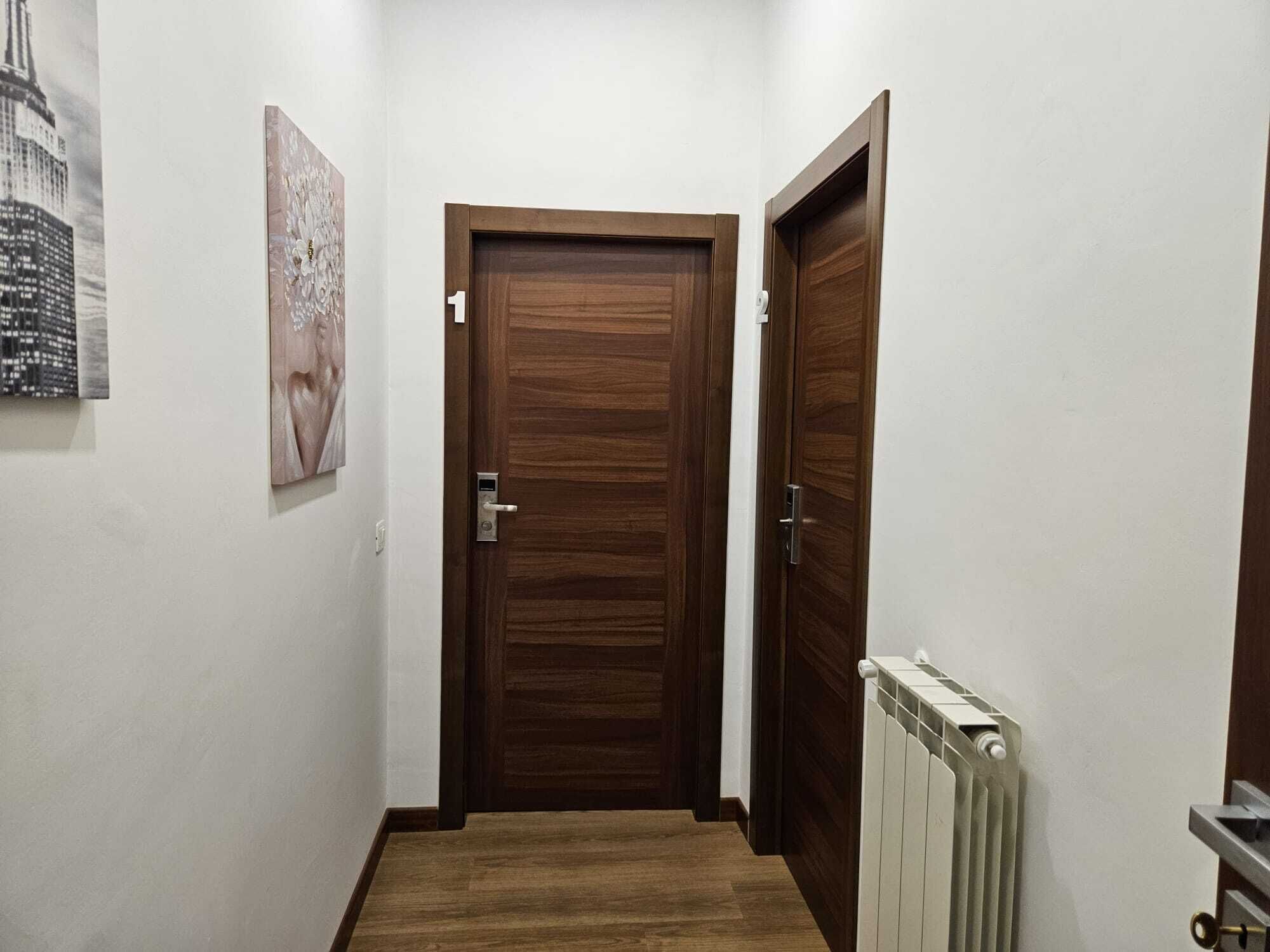 Ein Flur mit einer Holztür, einem Heizkörper und einem gerahmten Bild an der Wand.