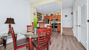 Una cocina moderna con armarios de madera, electrodomésticos de acero inoxidable y una zona de comedor con una mesa de vidrio y sillas de madera.