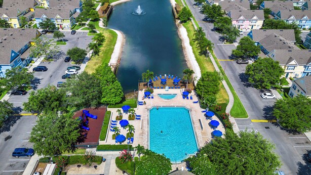 Vista aérea de un resort con piscina, zona de juegos para niños y un muelle sobre el agua.