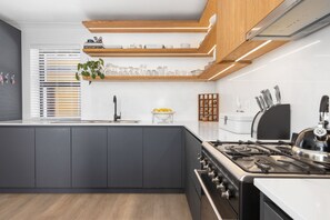 Een koelkast, een oven, kookgerei, borden en bestek, eettafels