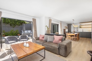 Un salon moderne avec un canapé, une table basse en bois et un coin repas comprenant une table et des chaises.