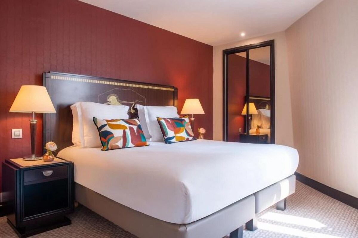 Une chambre d’hôtel avec un grand lit, deux tables de chevet avec des lampes et un miroir au mur.