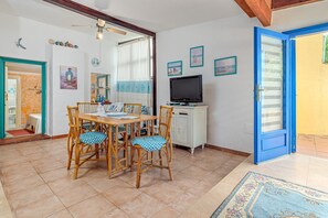 A dining area with a table, chairs, a television, and a cabinet. - Holiday Home 'Casa Taverna' with Private Terrace (Punta Pietra Bianca)