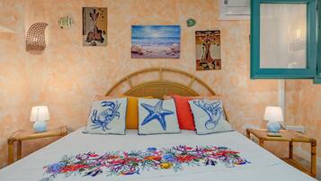 A bedroom with a bed, decorative pillows, wall art, and a window.