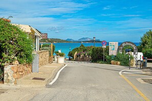 A coastal road with a stone wall, a sign for 'Vernetta Spa,' and a 'No Parking' sign.