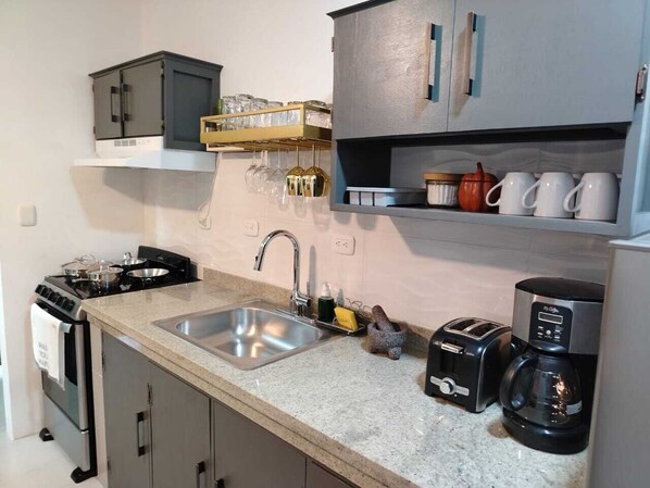 Una cocina equipada con lavamanos, estufa, tostadora y cafetera.