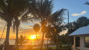 A sunset view with palm trees and a bridge in the background.