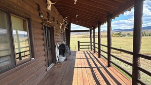 Une cabane en bois dotée d’un porche abrité, de grandes fenêtres et offrant une vue sur le paysage environnant.