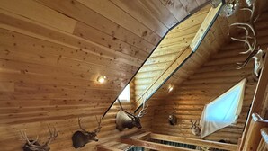 L’intérieur d’une cabane comprend une chambre à coucher située en mezzanine, des murs en bois et un coin repas.
