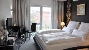 Een hotelkamer met een bed, een bureau met stoel, een televisie en een raam met gordijnen.