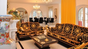 Een weelderige woonkamer met decoratieve banken, een kroonluchter en een eethoek.