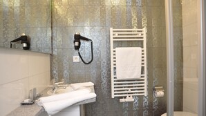 Een badkamer met een douche, wastafel en handdoekhouder.