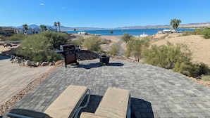 Un patio con sillones de descanso, una parrilla y vista al océano.