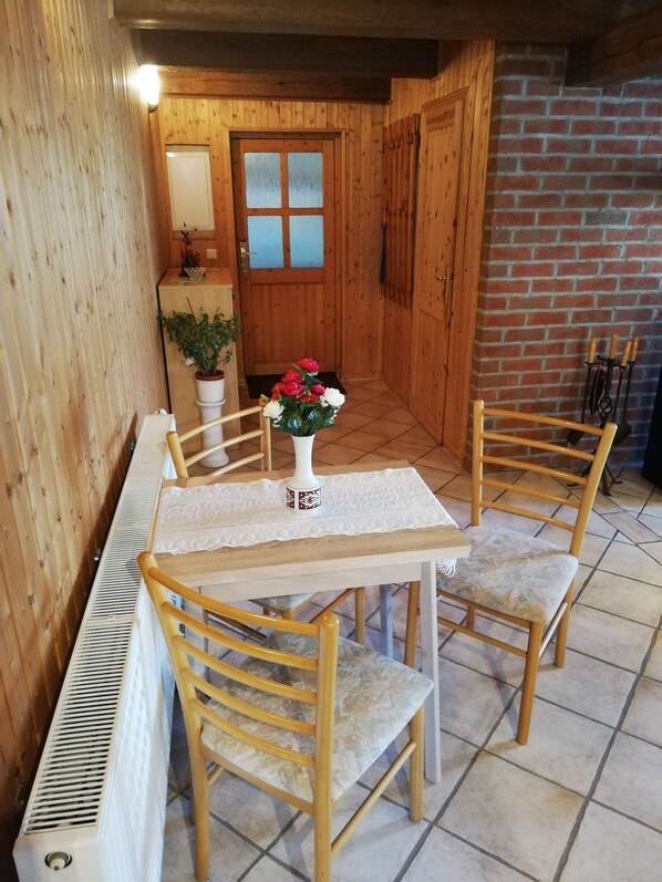 A wooden dining area with a table and chairs, a radiator, and a door with frosted glass panels.
