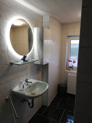 A modern bathroom with a sink, mirror, and a window with a view.