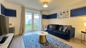 A modern living room with a dark blue sofa, a patterned rug, and a small round coffee table.