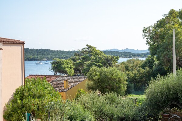 A coastal view with boats, trees, and a building with a tiled roof.