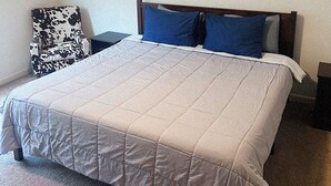 A bedroom with a large bed, a headboard, a wall-mounted artwork of vases, and a patterned armchair. - New Charming 3-bedroom/2.5 bathroom house in Metro Atlanta area (Decatur)